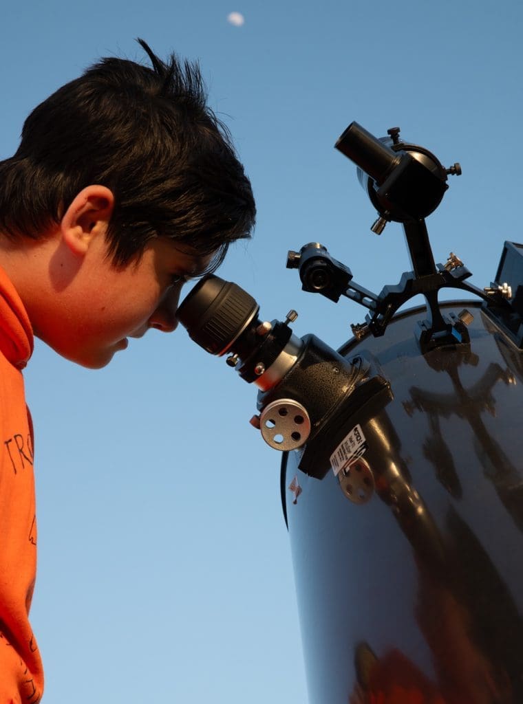 A young boy looking into a telescope at John Glenn Astronomy Park in Hocking Hills, Ohio